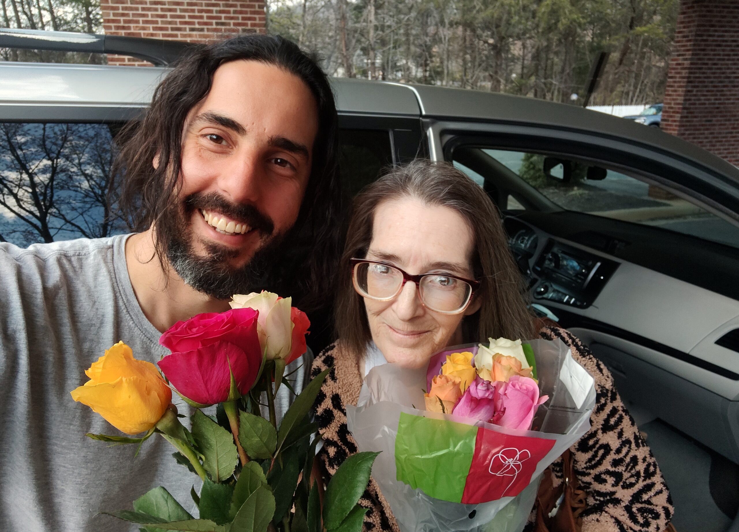 A picture of Jo and Gino holding flowers and spelling at the camera